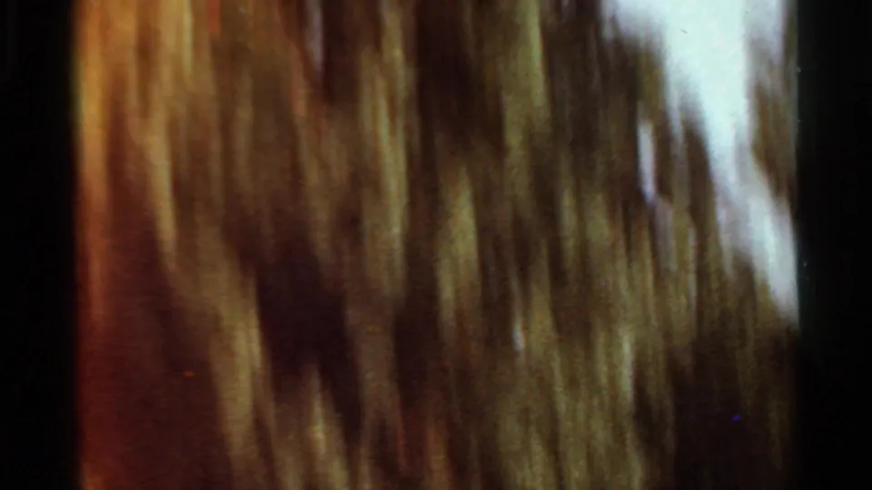 Close 8mm frame of moving fountain water, rendered as soft vertical streaks with warm color and visible film grain.
