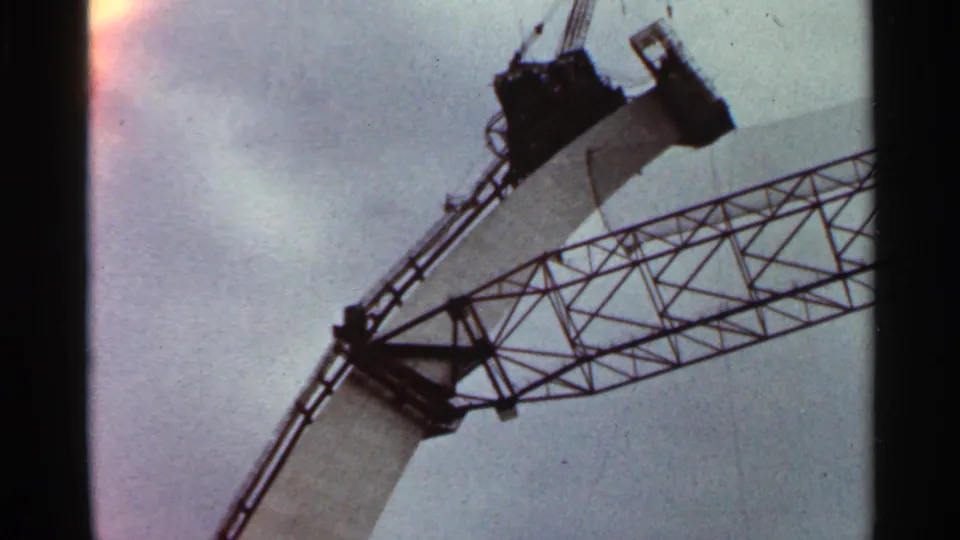 1966 Saint Louis construction view with a large crane and pale structural section framed against a cloudy sky near the Gateway Arch site.