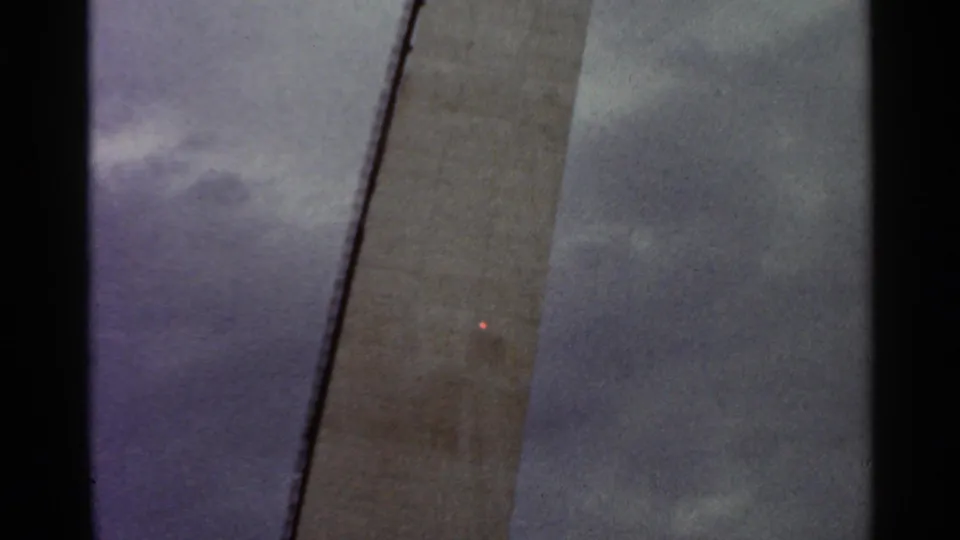 1966 Saint Louis 8mm frame showing a tall concrete construction surface rising against a cloudy sky.