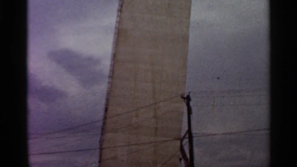1966 Saint Louis frame showing concrete construction beside cloudy sky, utility lines, and a pole.