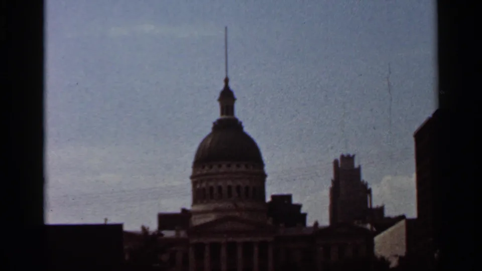 1966 Saint Louis exterior view of a domed civic building with spire, framed by dark foreground buildings and open sky.