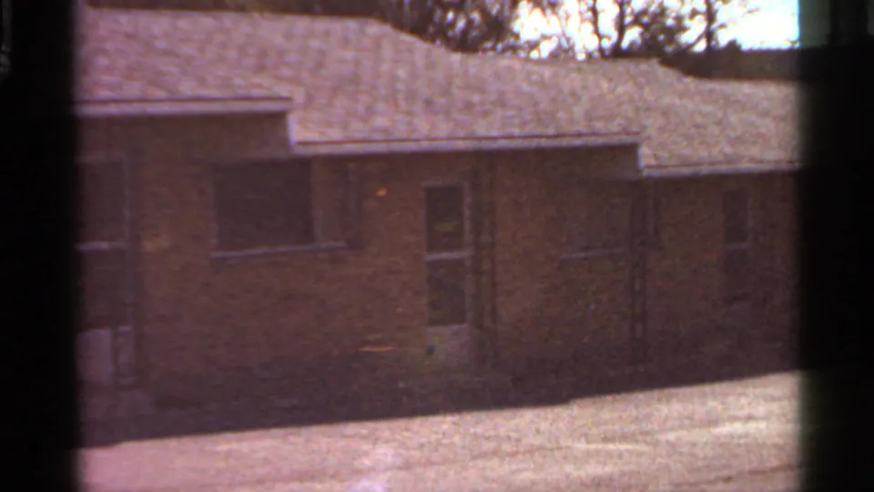 1966 Saint Louis frame showing a closer section of the brick apartment facade, with windows, roofline, and tree branches overhead.