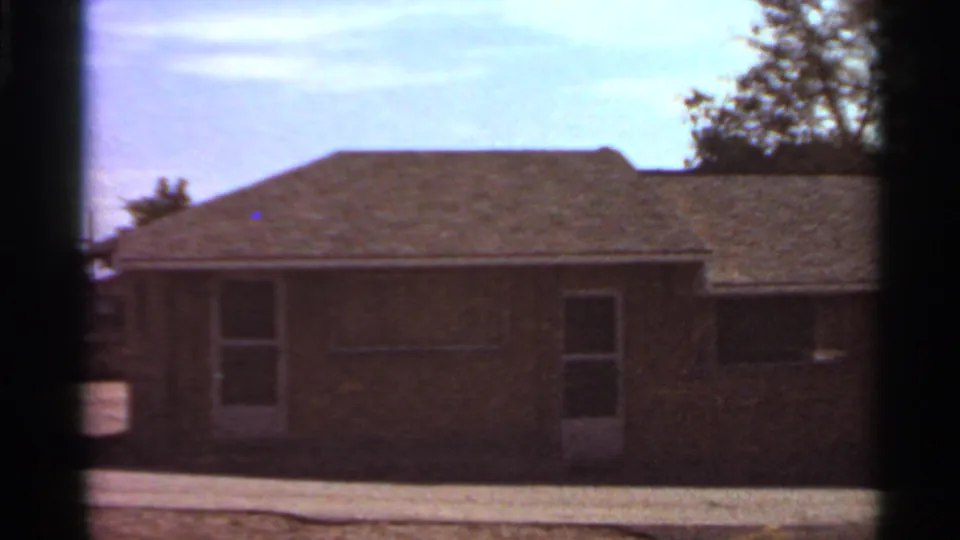 1966 Saint Louis residential exterior with a low brick home, narrow door, windows, and trees beyond the roofline.