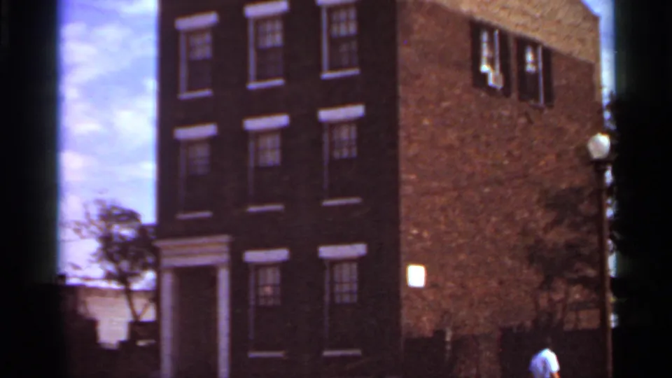 Brick residential building in Saint Louis, filmed from a low angle with windows, doorway, and sky visible.