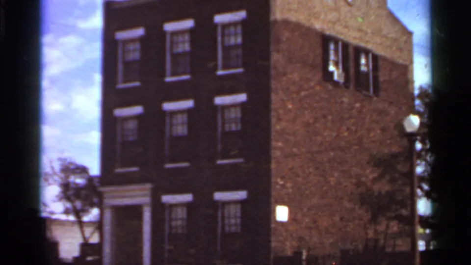 Saint Louis brick building exterior with rows of windows and a doorway, captured in faded 8mm color.