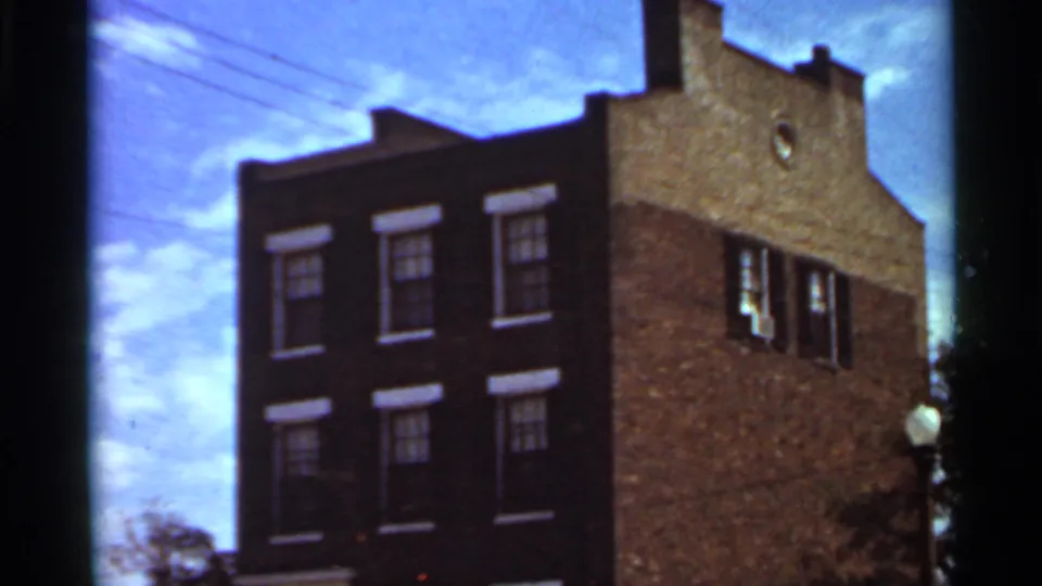 1966 Saint Louis 8mm frame showing the same brick building facade with soft focus, blue sky, and dark film gate border.
