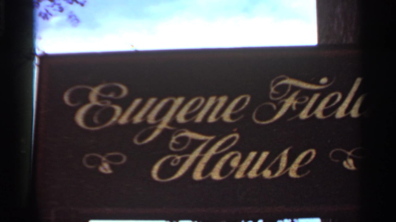 Dark wooden sign with gold script reading Eugene Field House beside a bright window opening.