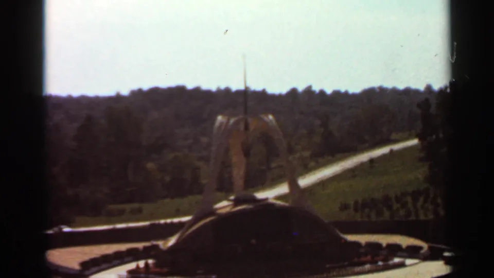 1966 8mm home-movie frame showing the Shrine of Our Lady of the Snows landscape, with the modernist shrine structure and surrounding greenery.
