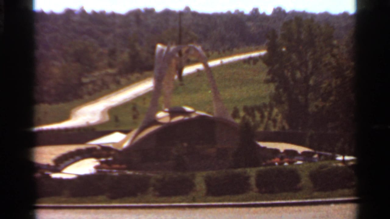 Saint Louis 1966 home-movie still showing the futuristic fountain from a slightly shifted angle within landscaped grounds.