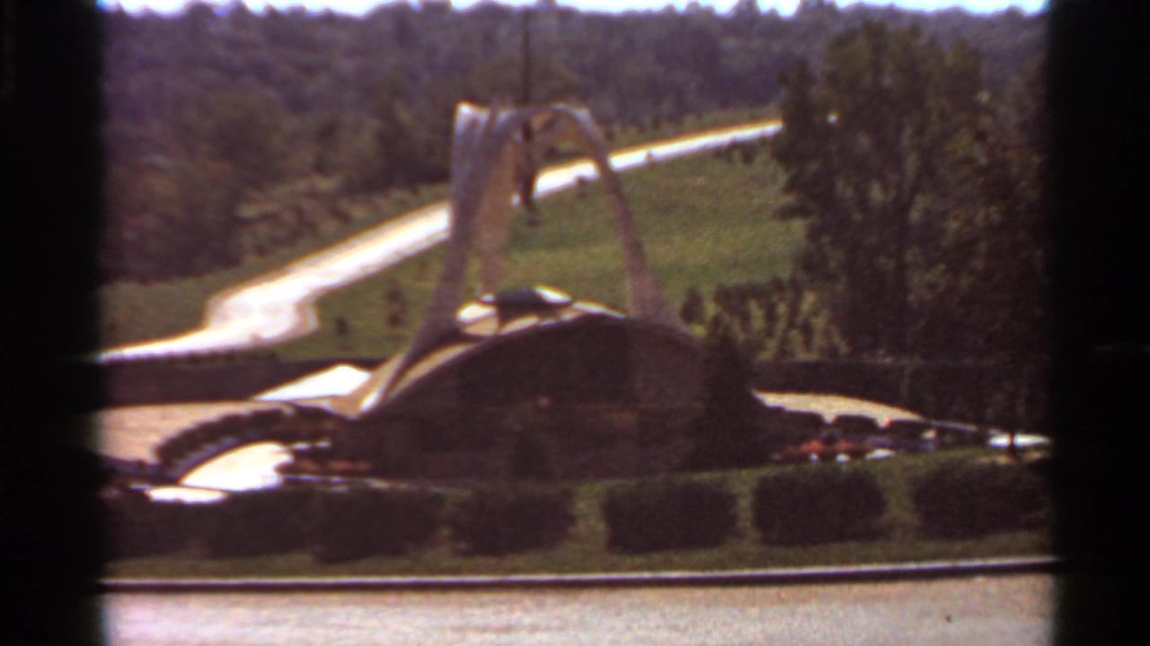 Final 1966 Saint Louis frame showing the decorative fountain in soft 8mm color with surrounding hedges, lawn, road, and trees.