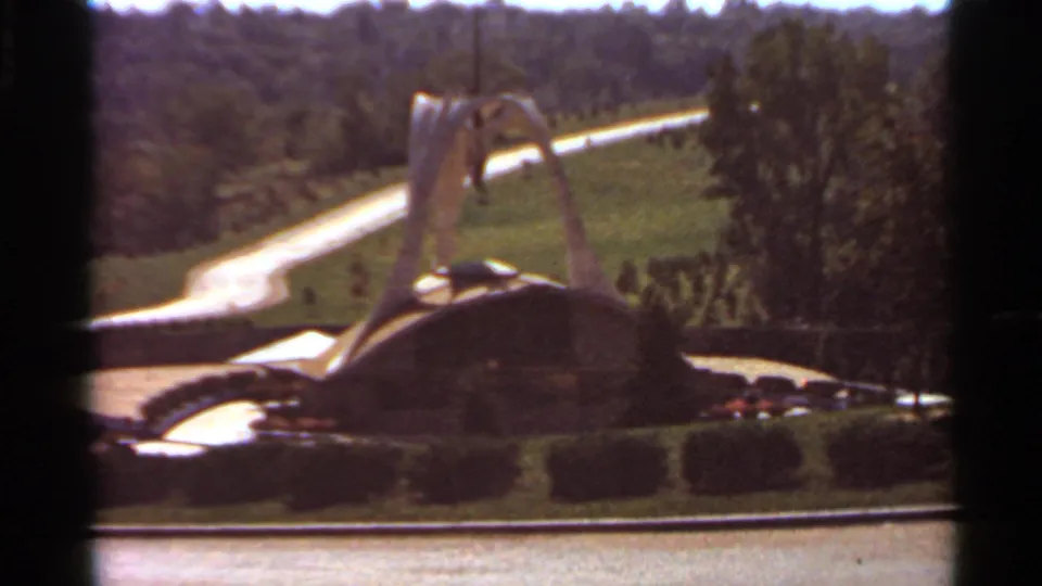 Final 1966 Saint Louis frame showing the decorative fountain in soft 8mm color with surrounding hedges, lawn, road, and trees.