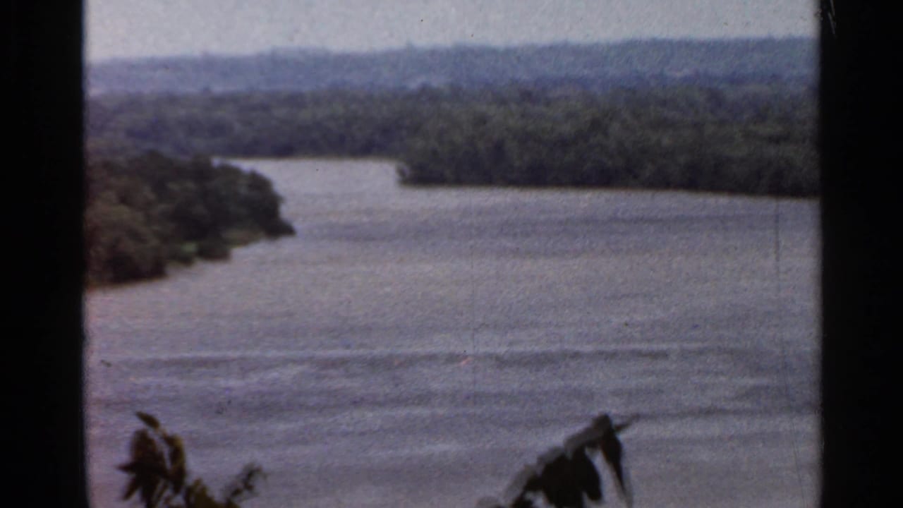 1966 8mm home-movie view of a broad river near Saint Louis, Missouri, with wooded banks and dark framing edges in the foreground.
