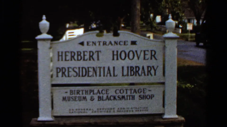 1966 8mm frame showing a readable Herbert Hoover Presidential Library entrance sign with references to the Birthplace Cottage Museum and Blacksmith Shop.