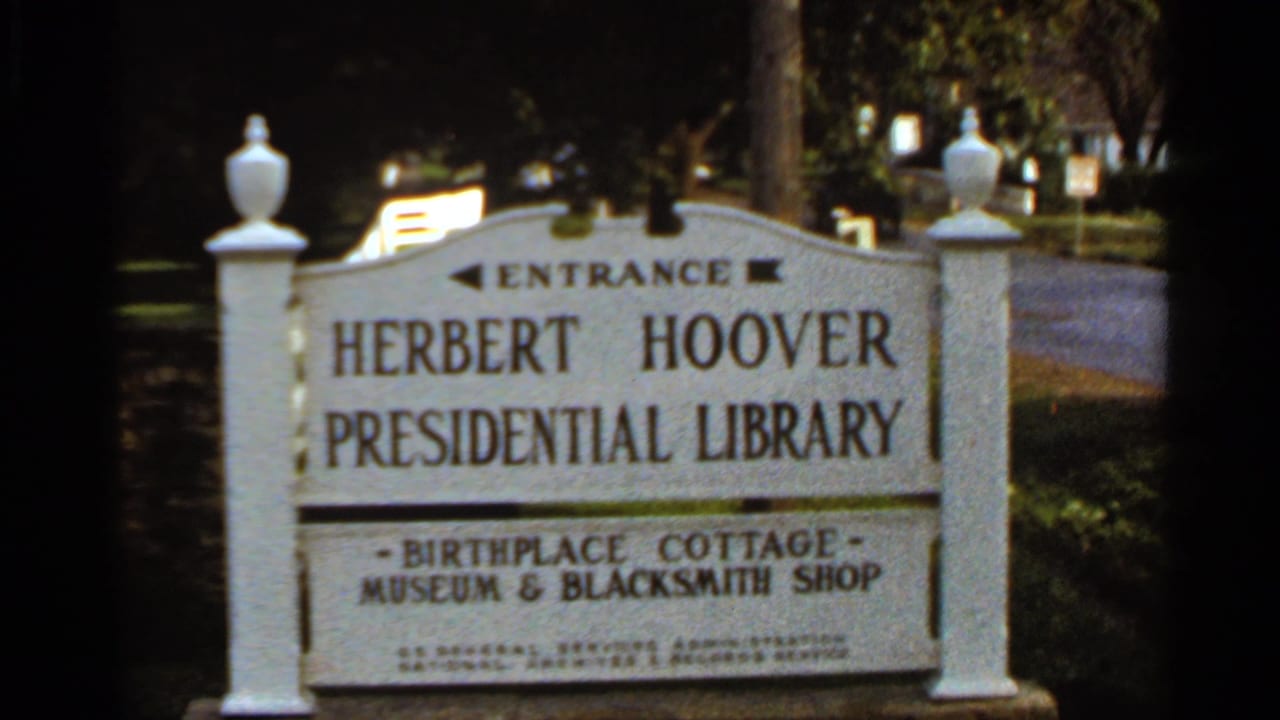 Entrance sign for the Herbert Hoover Presidential Library beside trees and roadway.