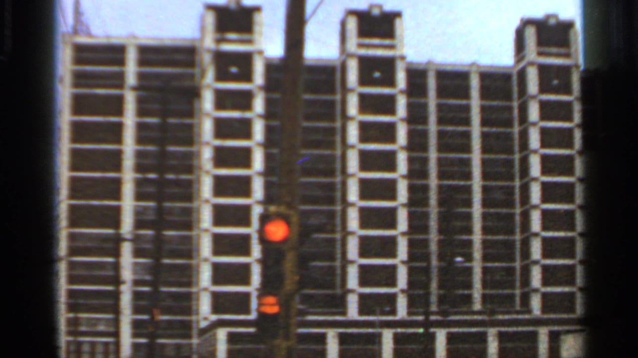 1966 Saint Louis street view of a tall gridded building facade with a red traffic signal in the foreground.