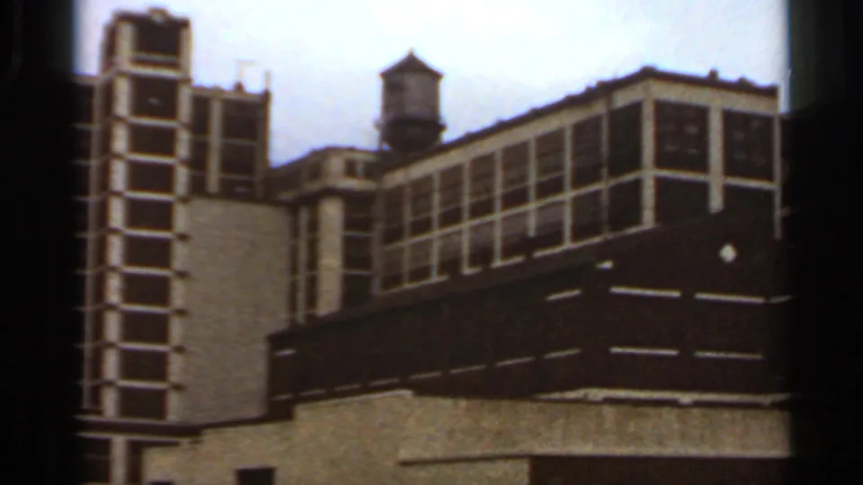 1966 Saint Louis street view of a yellow and brown multi-story building with gridded windows and a small rooftop water tower.