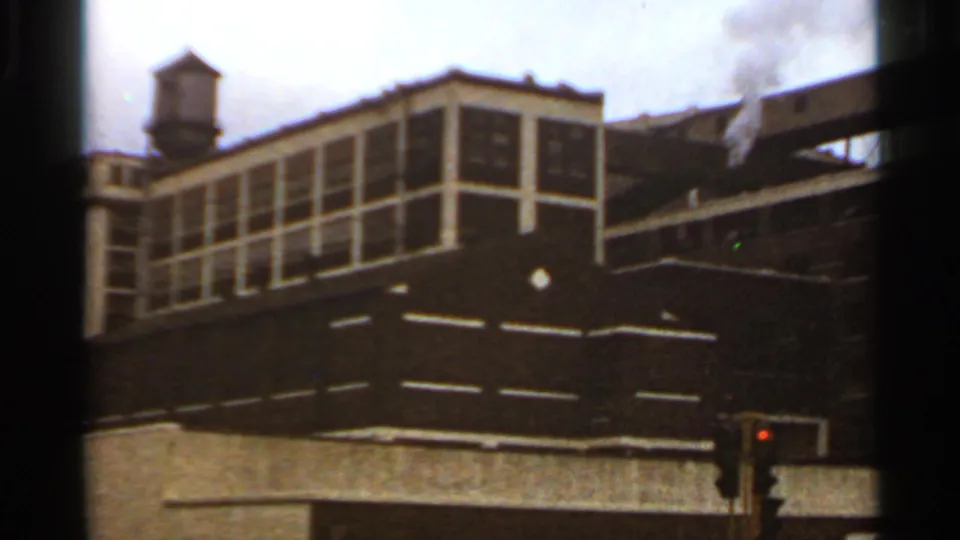1966 Saint Louis exterior showing the gridded upper facade, rooftop water tower, cloudy sky, and a traffic light in the foreground.
