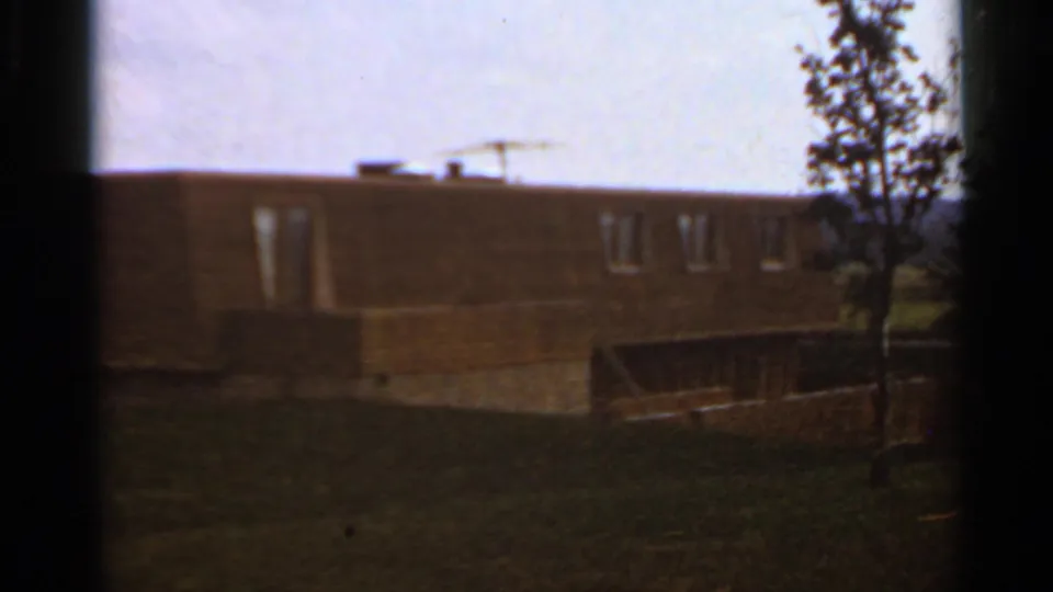 1966 Saint Louis school exterior with brick walls, roofline, lawn, and a small tree under a pale sky.