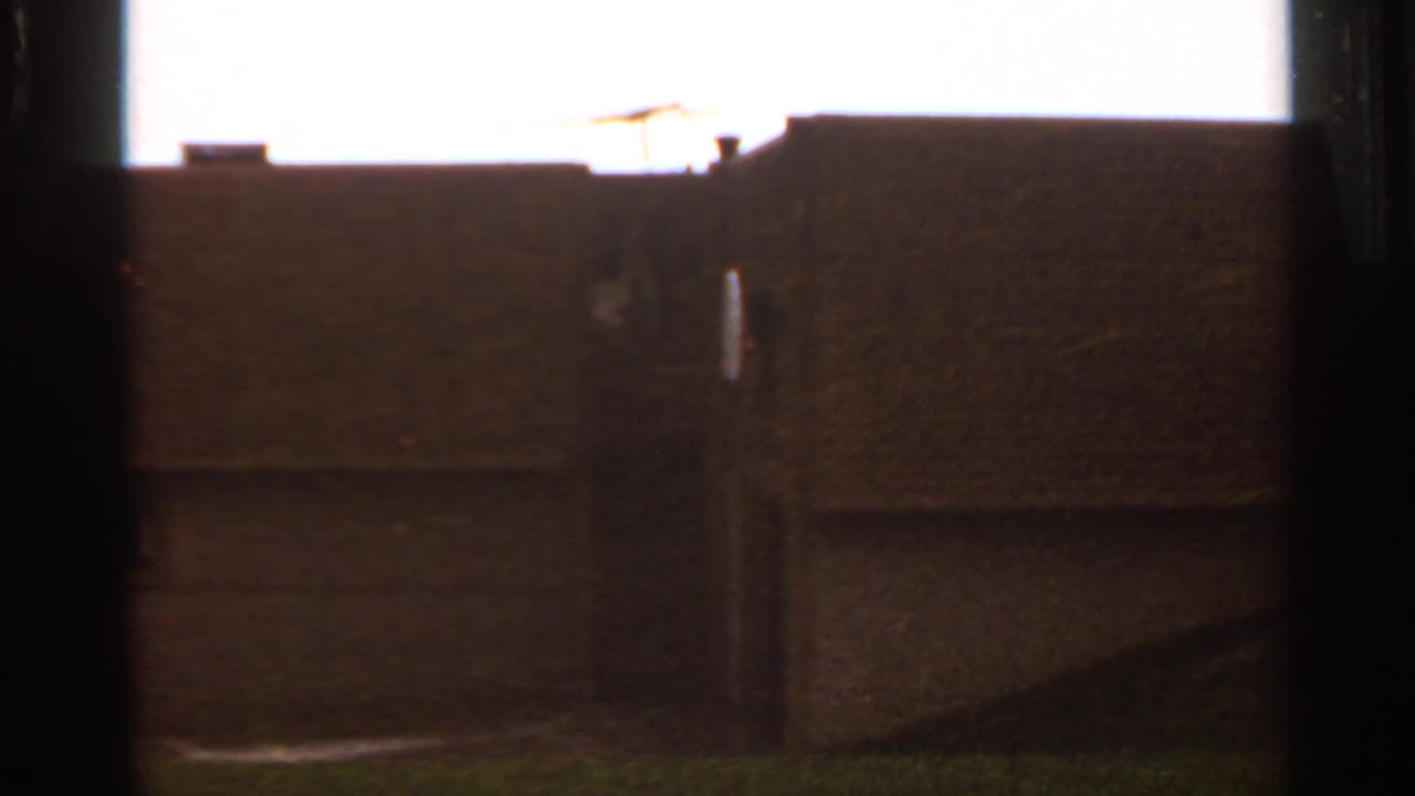 Dark building wall and roofline seen through heavy vertical frame edges.