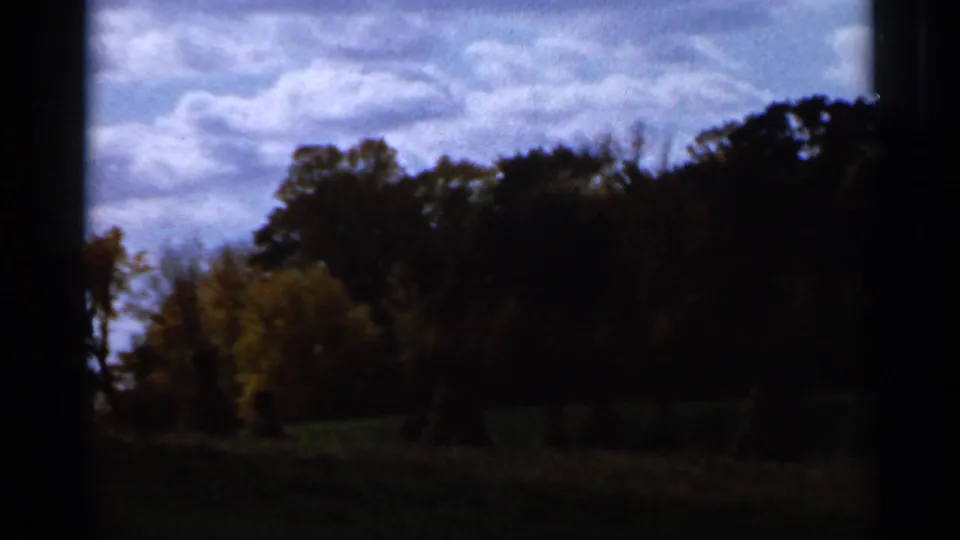 1966 Sauk Centre, Minnesota frame with a darker tree line, shadowed field, and cloudier sky as exposure and weather appearance shift.