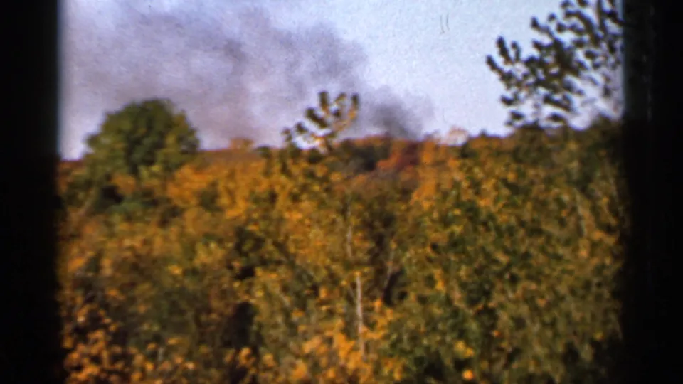 Final 1966 Sauk Centre frame shows smoke over a tree-covered hillside, with visible 8mm gate edges and soft color shifts.