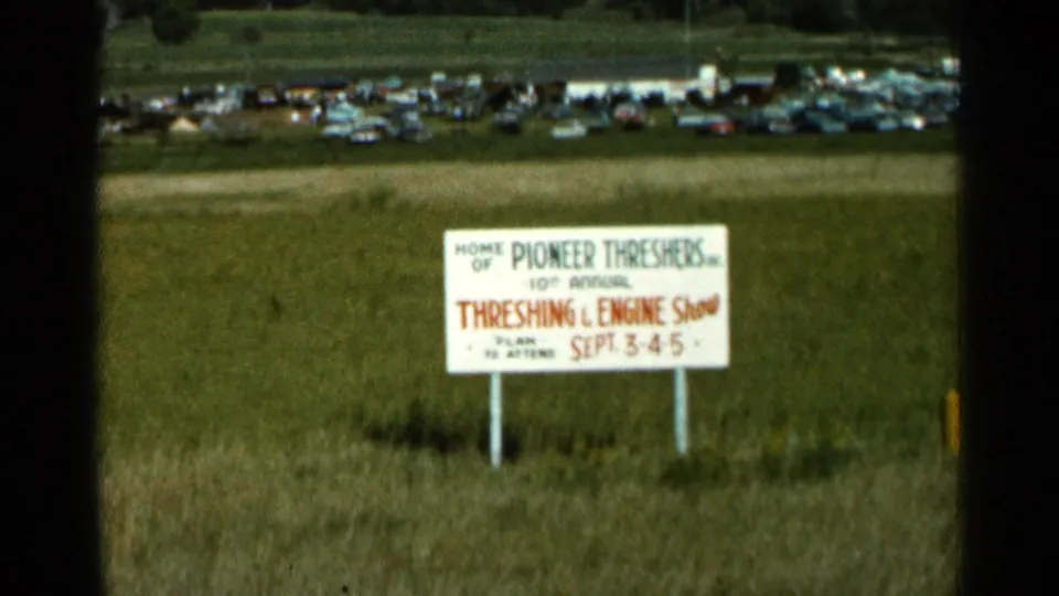 1966 Wauseon, Ohio frame with the Pioneer Threshers show sign centered against grass and a distant parking area.