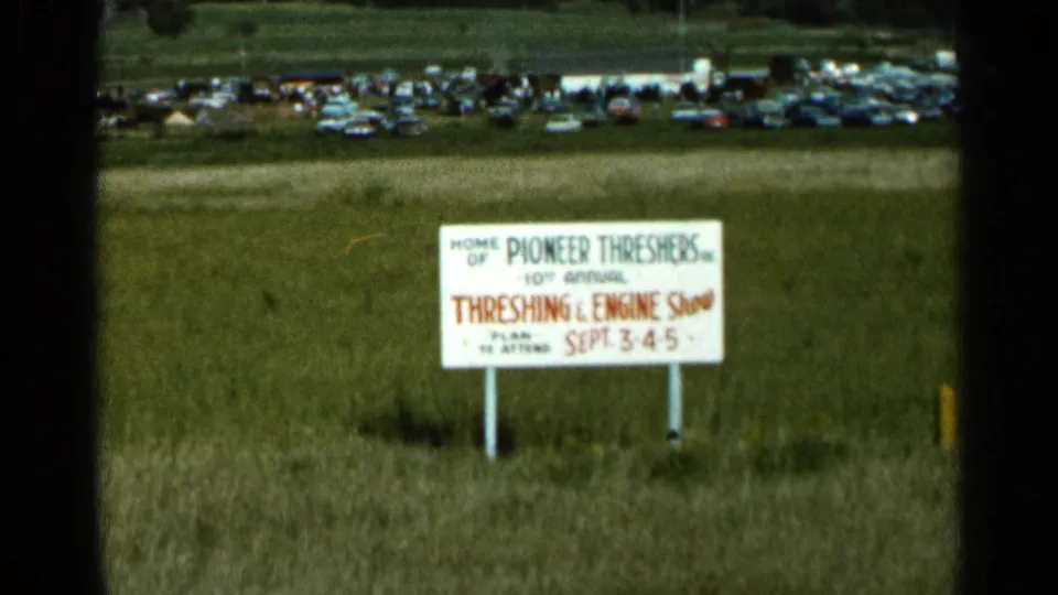 1966 Wauseon, Ohio frame showing the 10th Annual Threshing and Engine Show sign near a distant event parking area.