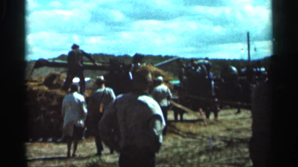 1966 rural Ohio show scene with workers and spectators gathered near hay baling equipment under a bright cloudy sky.