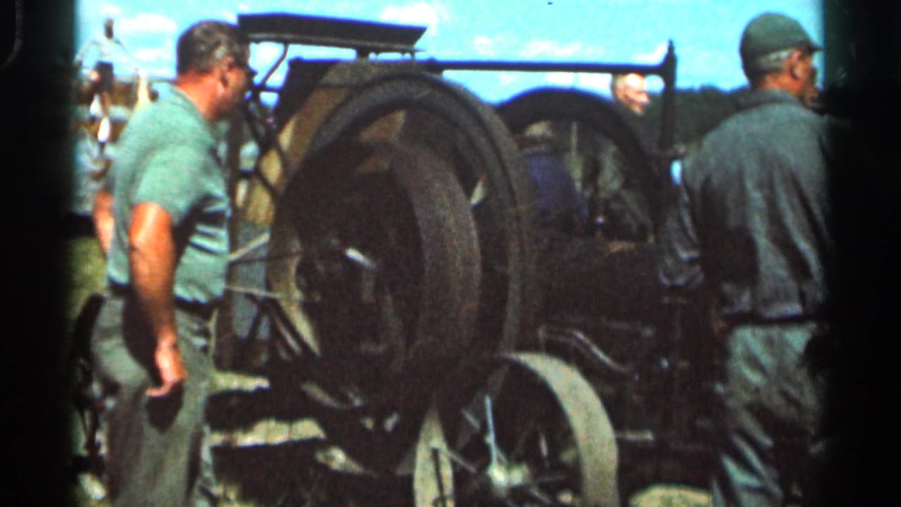 1966 Wauseon, Ohio 8mm frame showing adult men gathered near a black steam tractor at a rural fair or exhibition.