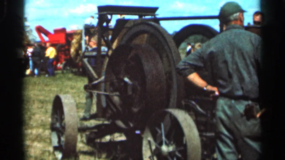 Home-movie frame from the 1966 Wauseon, Ohio fair showing the rear wheels of a steam tractor and nearby spectators.