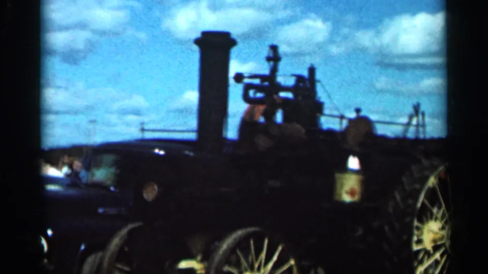 Silhouetted 8mm view of the steam tractor's smokestack, upper machinery, and wheels at the Wauseon fairground.