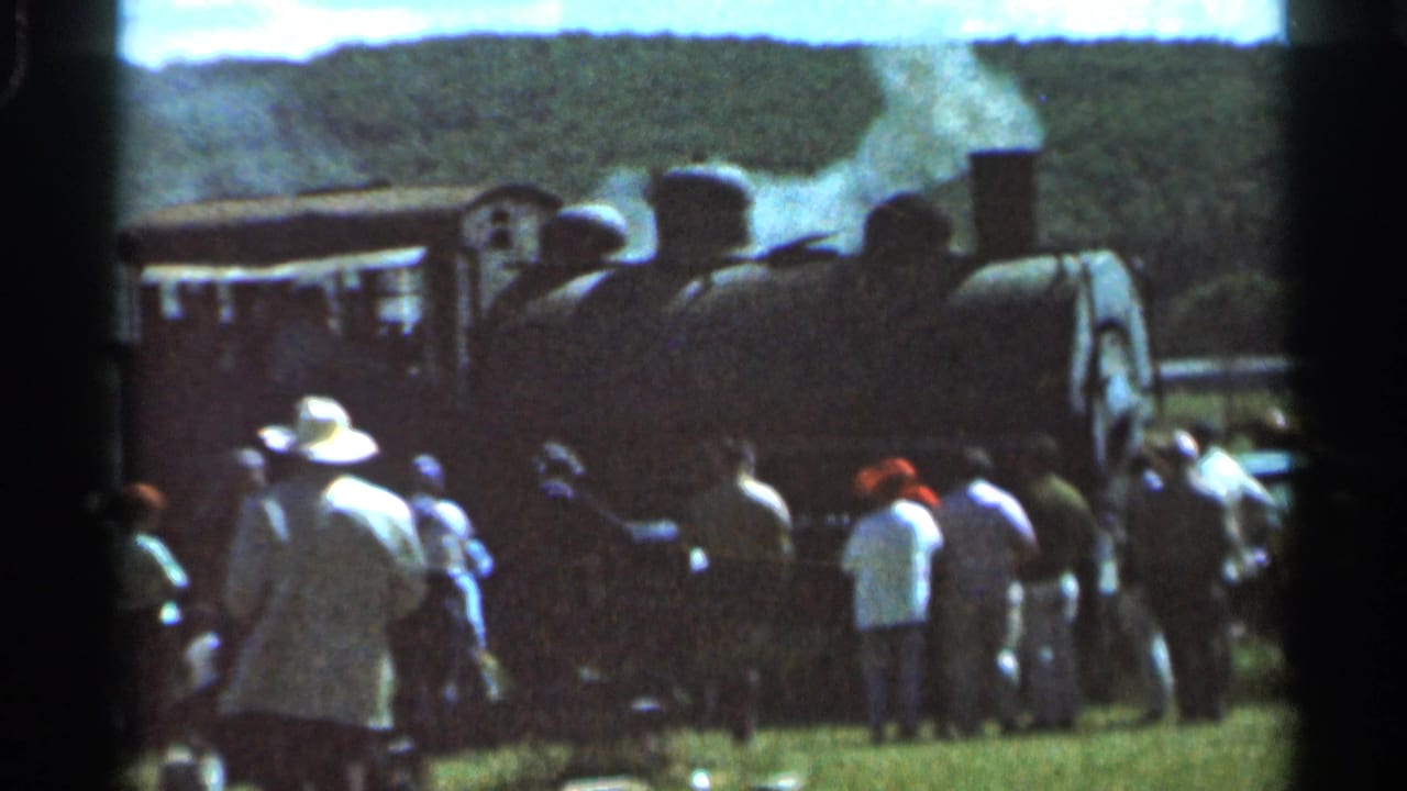 1966 Wauseon, Ohio home-movie frame showing onlookers gathered near a steam locomotive giving off white smoke.
