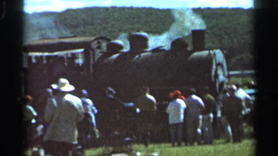 1966 Wauseon, Ohio home-movie frame showing onlookers gathered near a steam locomotive giving off white smoke.