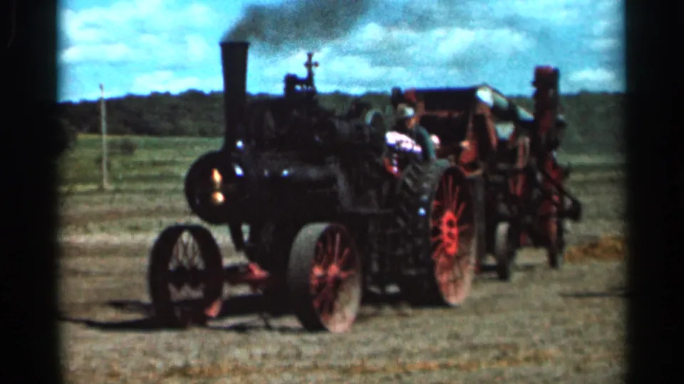 A black steam-powered tractor with red spoked wheels operates in an open Wauseon, Ohio field in the 1966 home-movie clip.
