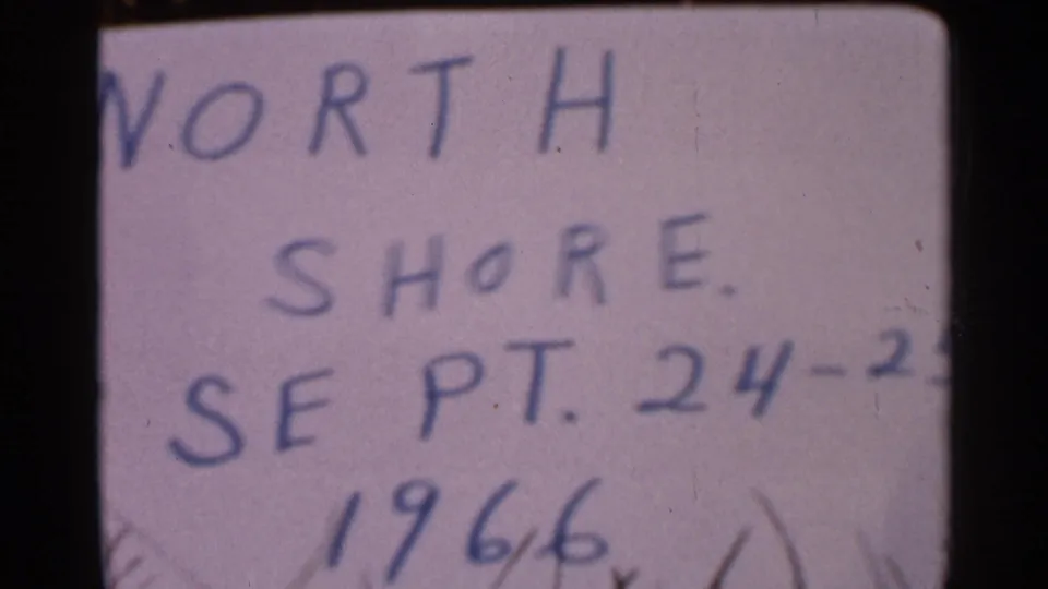 Handwritten North Shore title card remains on screen in the 1966 home-movie clip, with soft 8mm texture and partial segment notation.