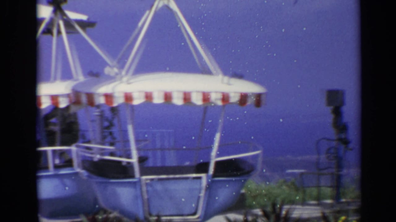 1967 US Virgin Islands home-movie frame showing a blue carnival gondola ride with a red-and-white striped canopy.