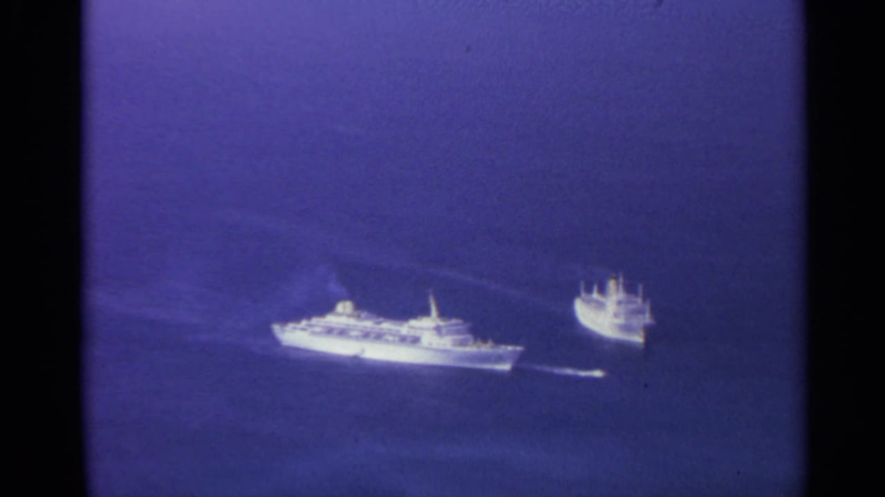 Two bright ships on deep blue water with faint wakes behind them.