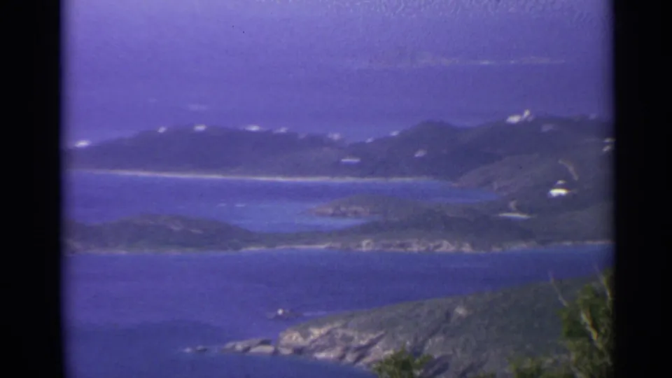 1967 8mm view of U.S. Virgin Islands hills, shoreline, and blue water from an elevated vantage point.