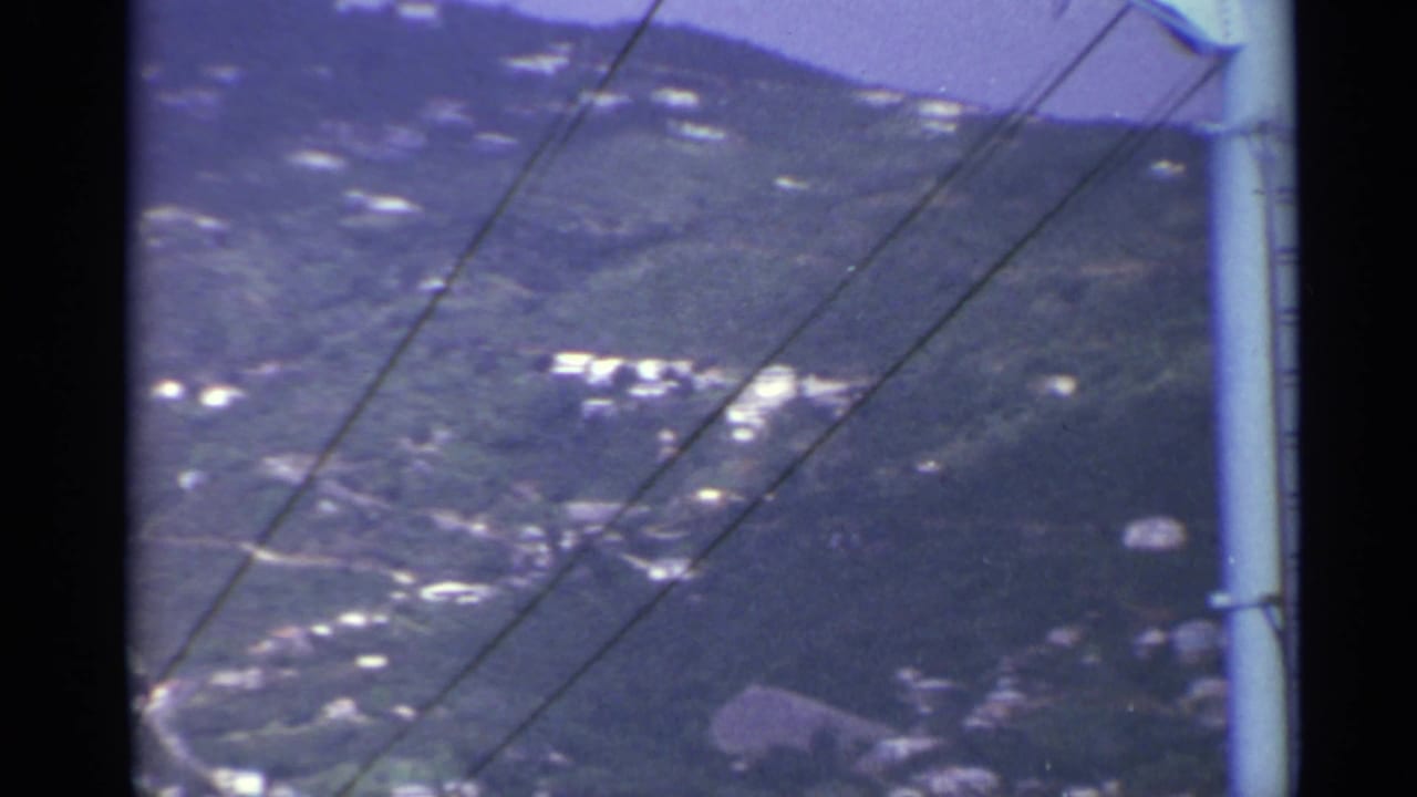 Mountain slope with hillside buildings, diagonal power lines, and a pole edge at the right.