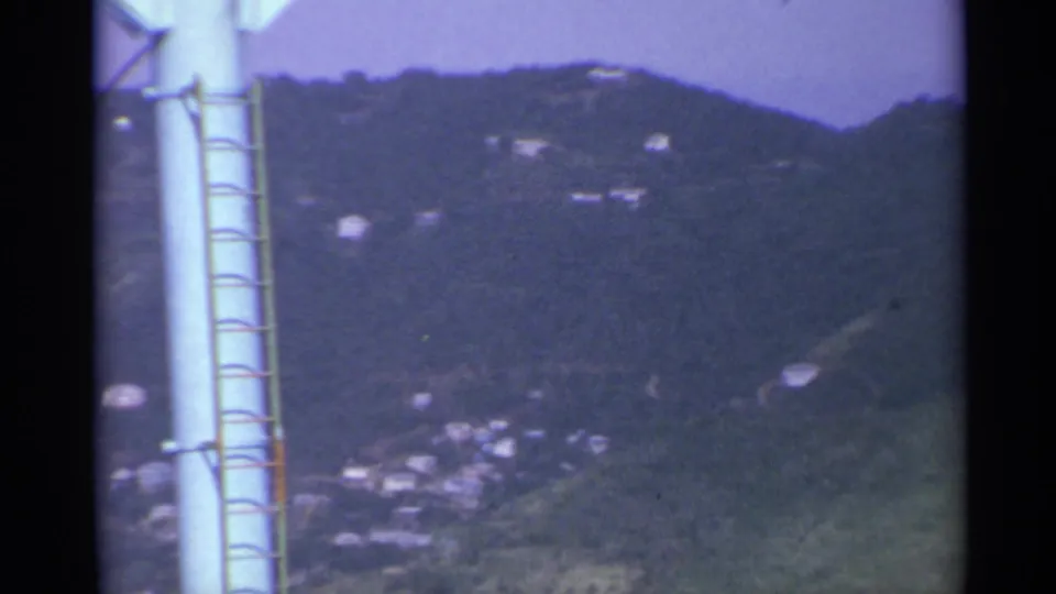 Final frame shows the laddered utility pole in the foreground and a dark green US Virgin Islands hillside dotted with small buildings.