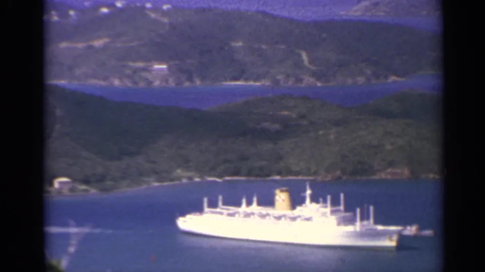 1967 US Virgin Islands home-movie frame showing a large white ship below an elevated coastal viewpoint.