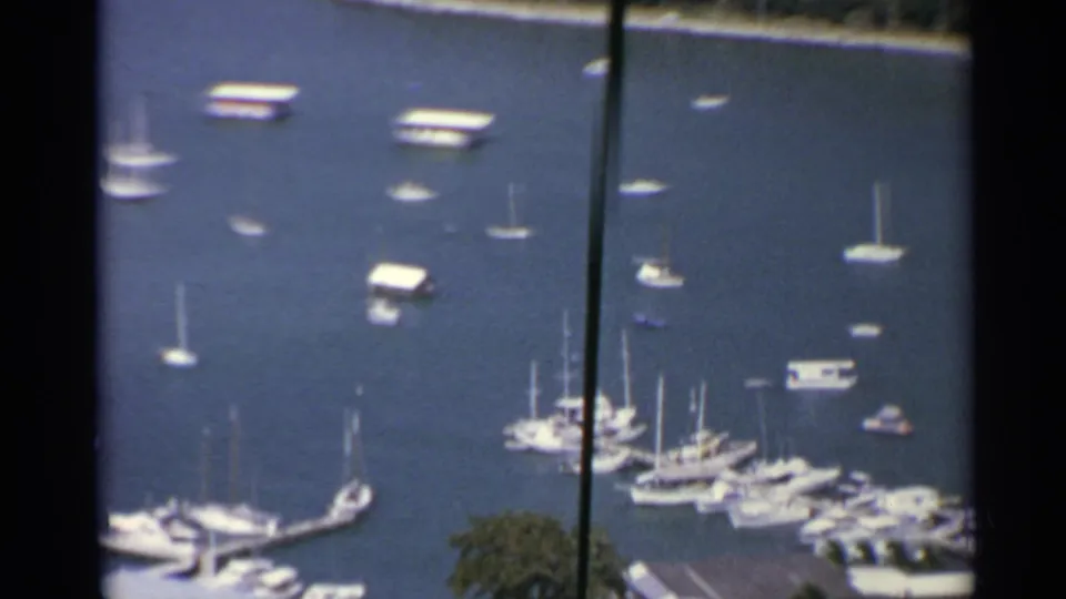 Elevated 1967 US Virgin Islands harbor view with anchored sailboats, clustered marina docks, and shoreline greenery.