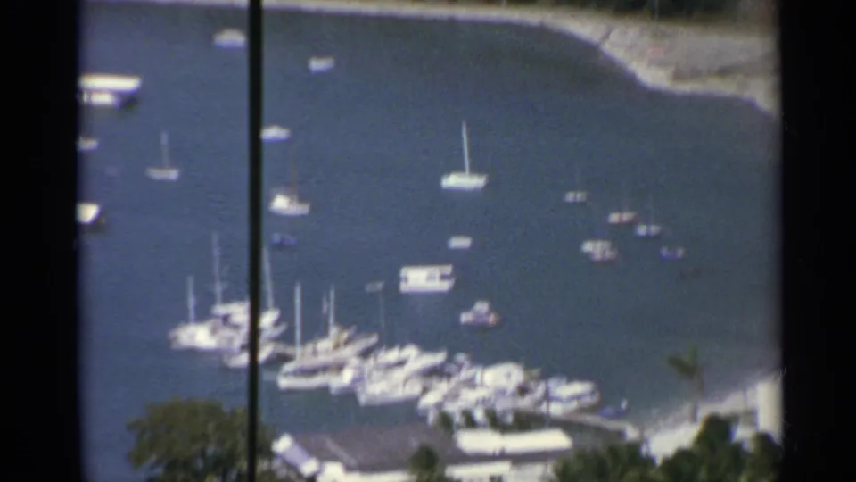 1967 US Virgin Islands marina view showing grouped boats, floating docks, shoreline structures, and a pale coastal edge.