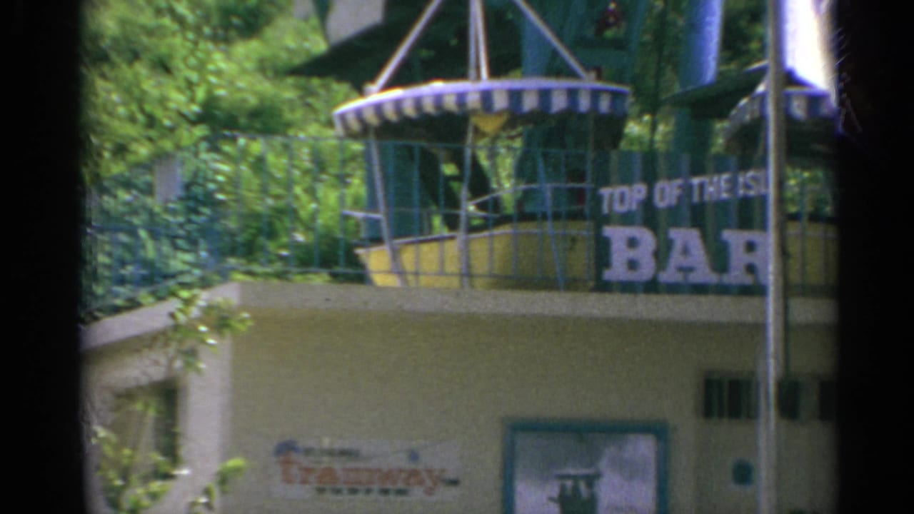 1967 US Virgin Islands home-movie frame showing the Top Of The Island Bar sign above a sunlit building exterior with balcony railings.