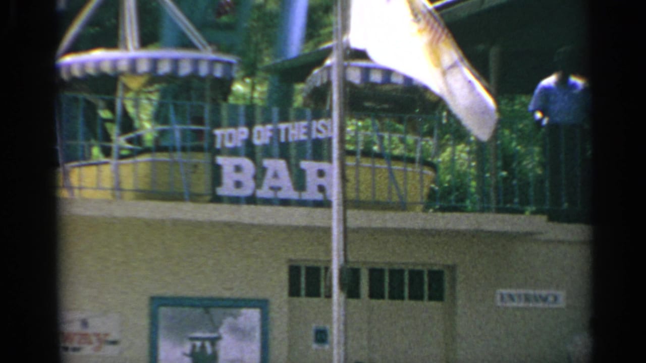 Bar sign, balcony, flagpoles, and an entrance sign on the building facade.