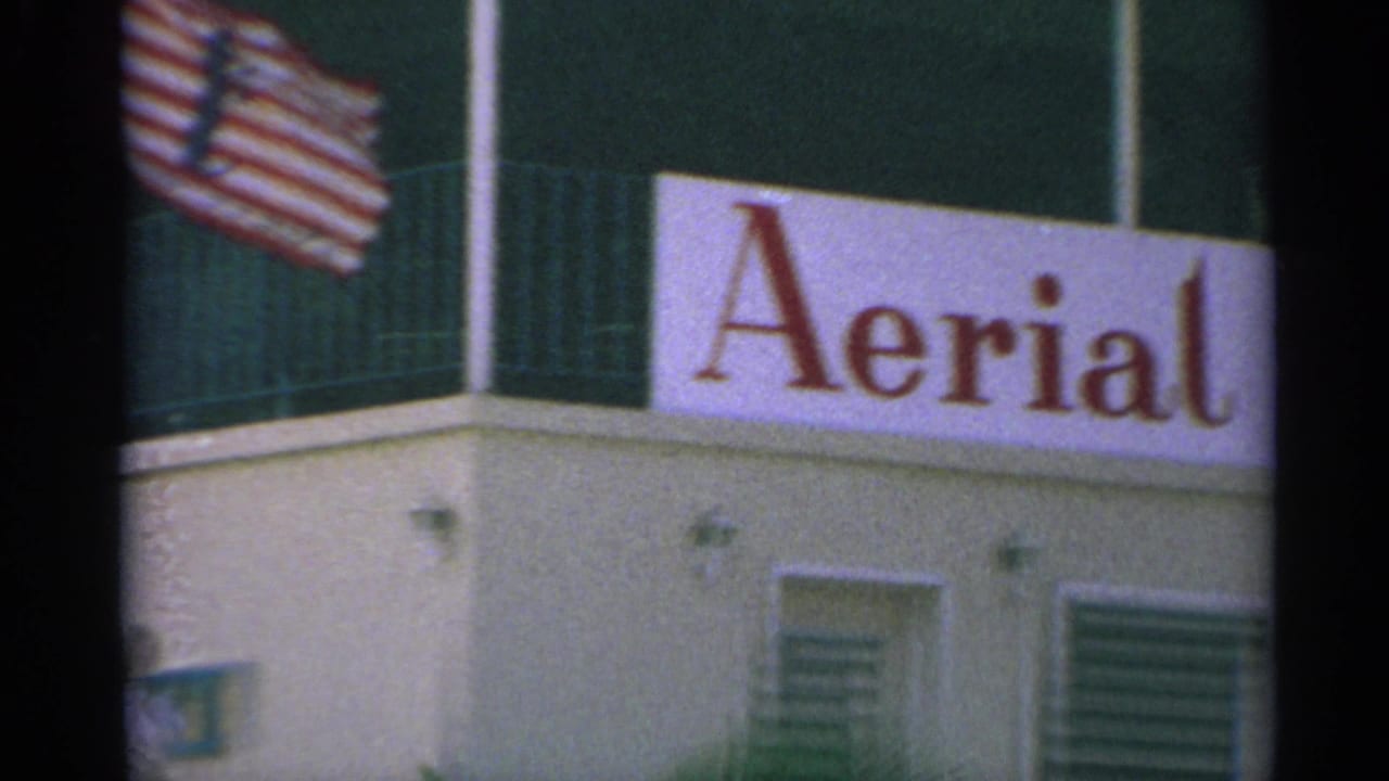 American flag above a building corner with part of an Aerial sign.
