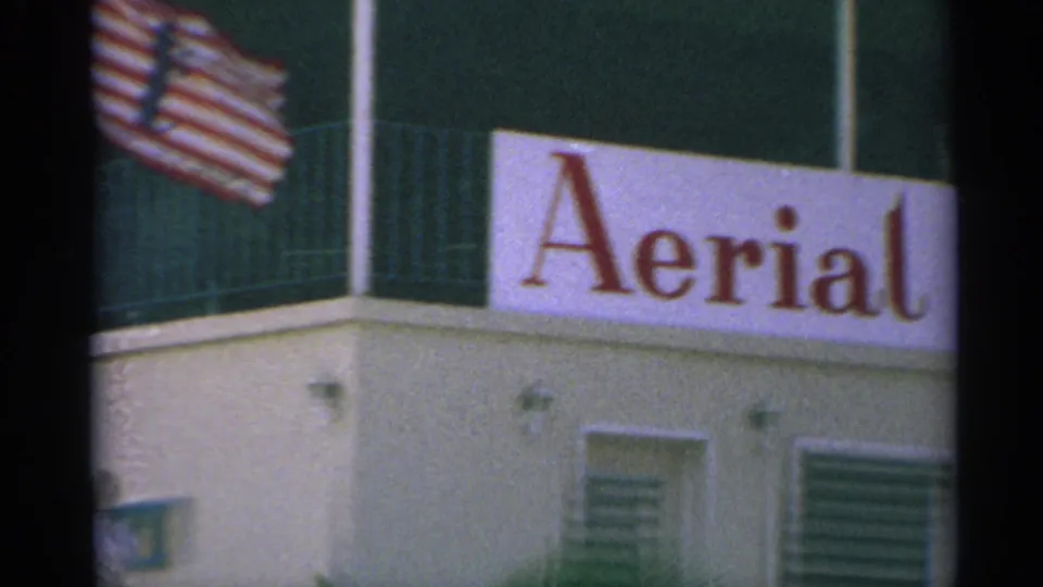 1967 8mm US Virgin Islands frame with an American flag over a building facade and partial Aerial signage.