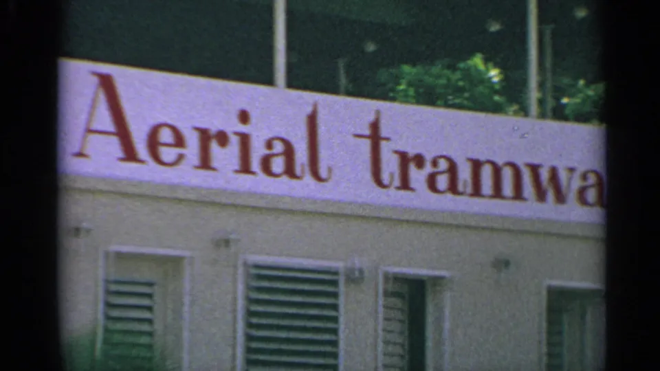 1967 8mm US Virgin Islands frame showing the Aerial tramway sign across a station building facade.