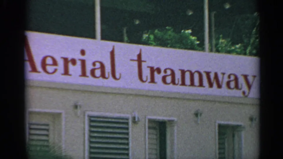 1967 8mm view of a red aerial tramway sign on a light building in the US Virgin Islands.