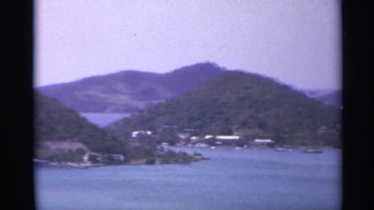 Blue water and green hills seen from an elevated island viewpoint.